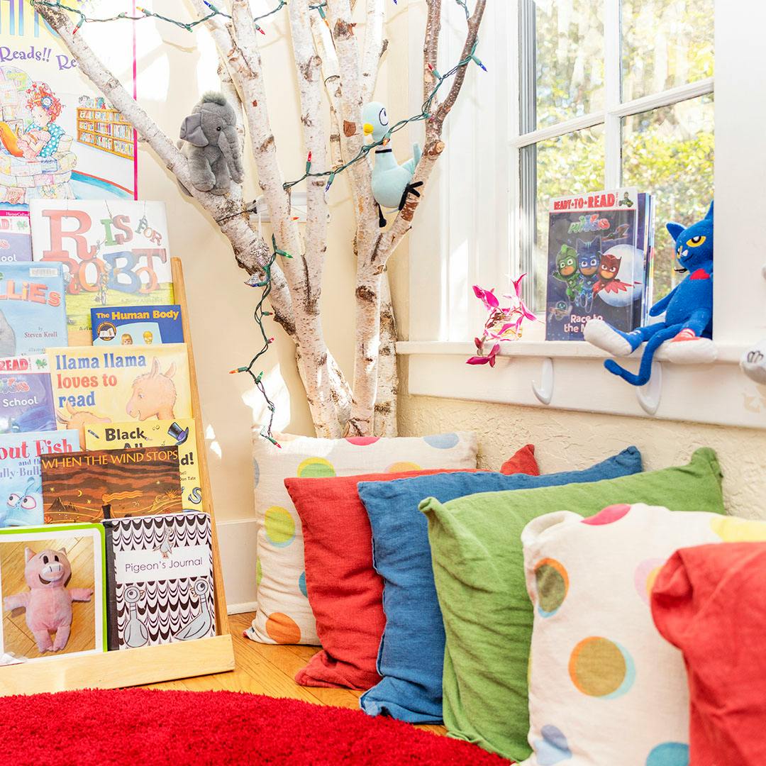 Children's reading nook with colorful pillows, books, and a stuffed animal