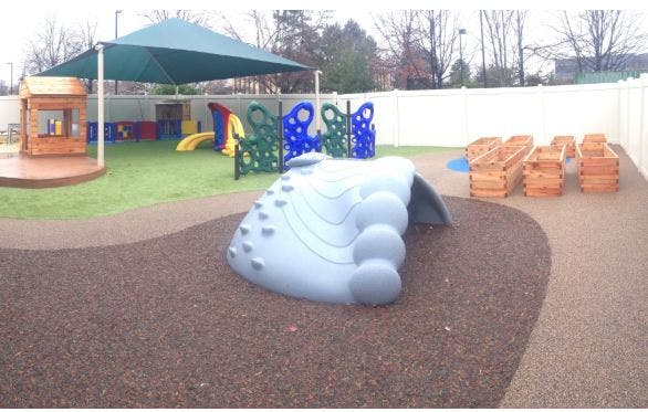 Outdoor playground with climbing structure, slides, and shade canopy