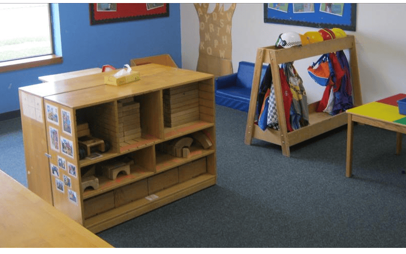 Classroom with wooden block shelf, coat rack, and small table