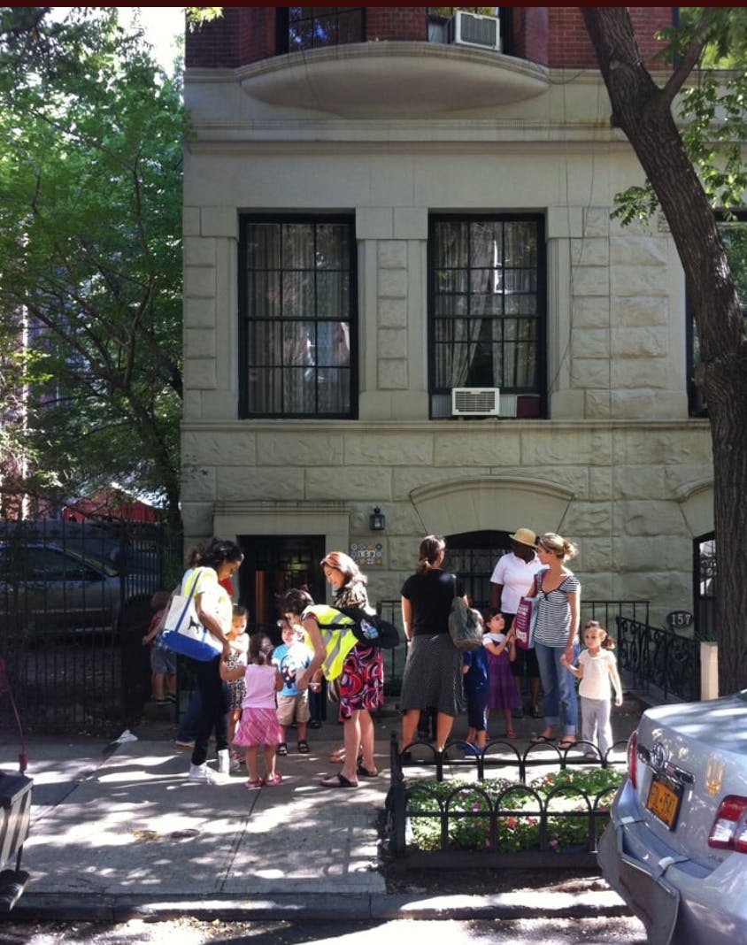 Adults and children gathered on a sidewalk in front of a building
