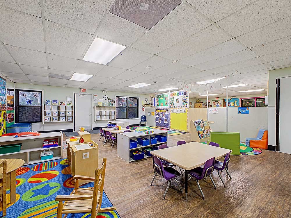 Colorful classroom with small tables and chairs, shelves, and learning materials