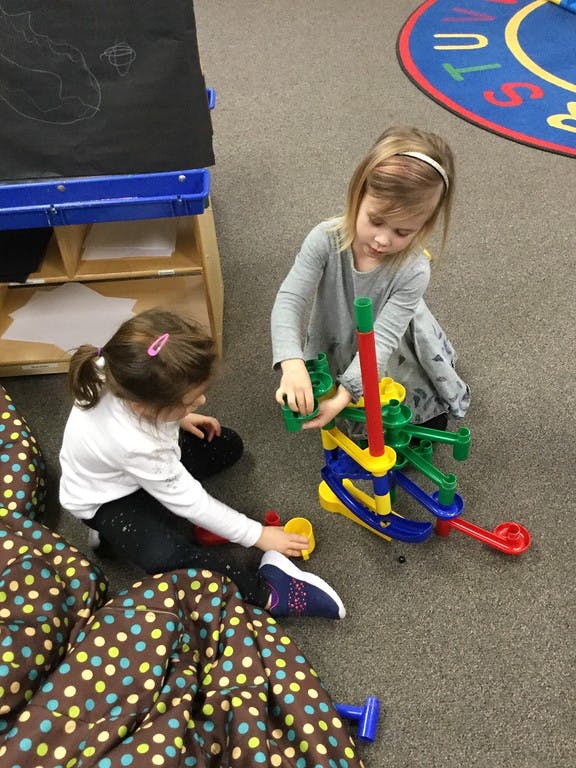 Two children playing with a colorful marble run toy on the floor