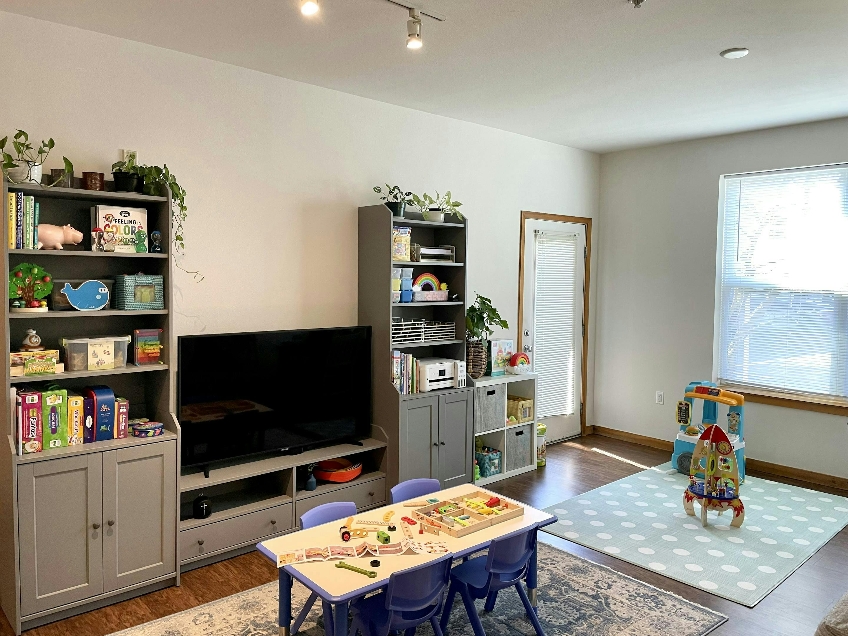 Living room with TV, bookshelves, and child's play table