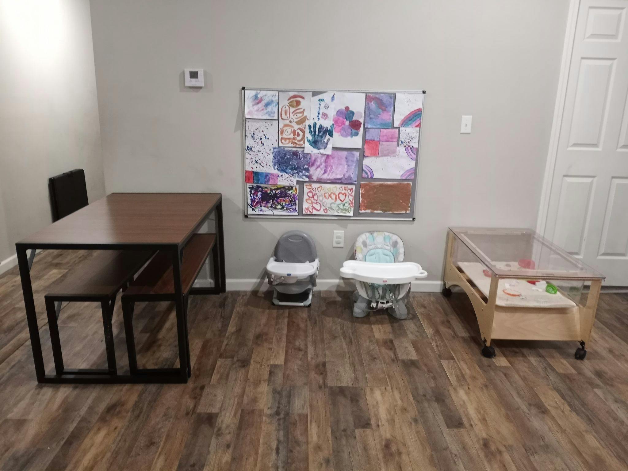 Room with table, benches, baby seats, and a crib