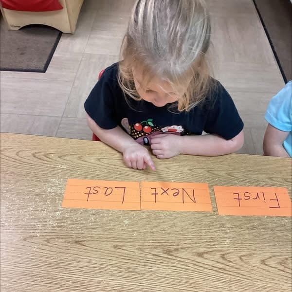 Child pointing at word cards on a table