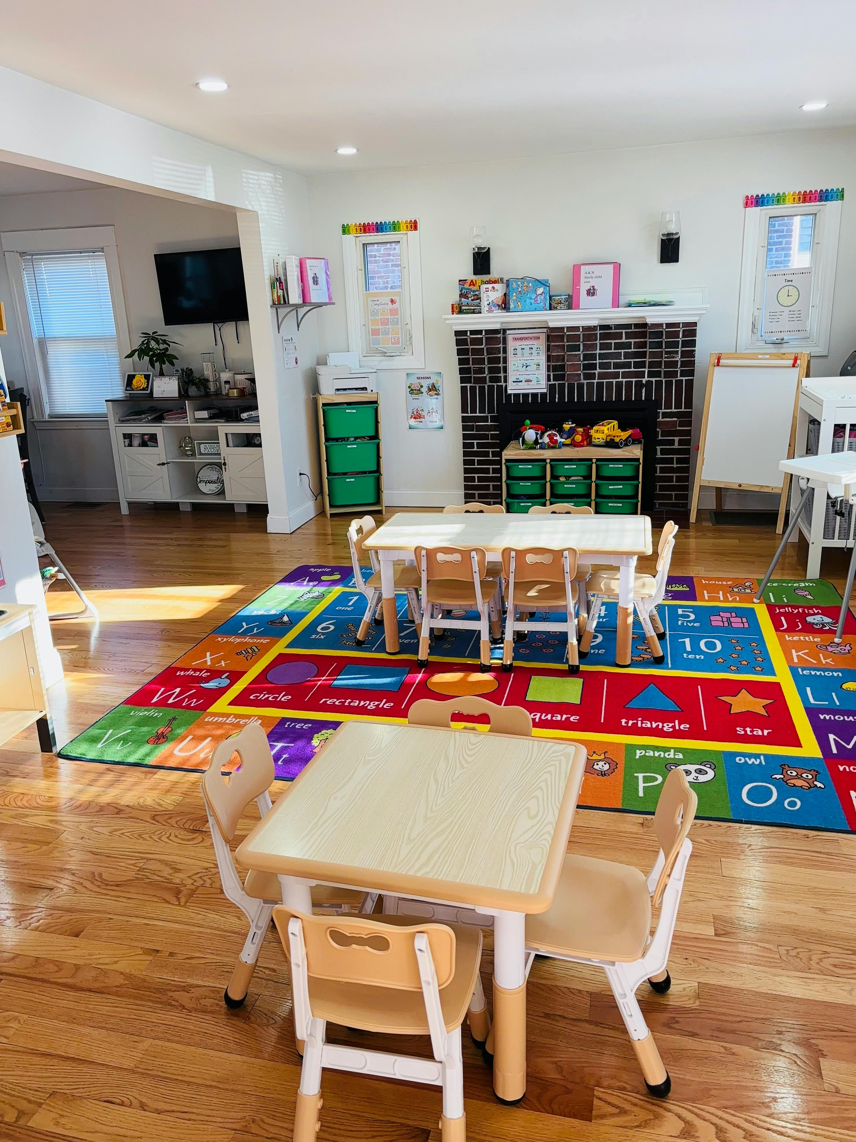 A colorful rug with letters and shapes on a wooden floor in a playroom
