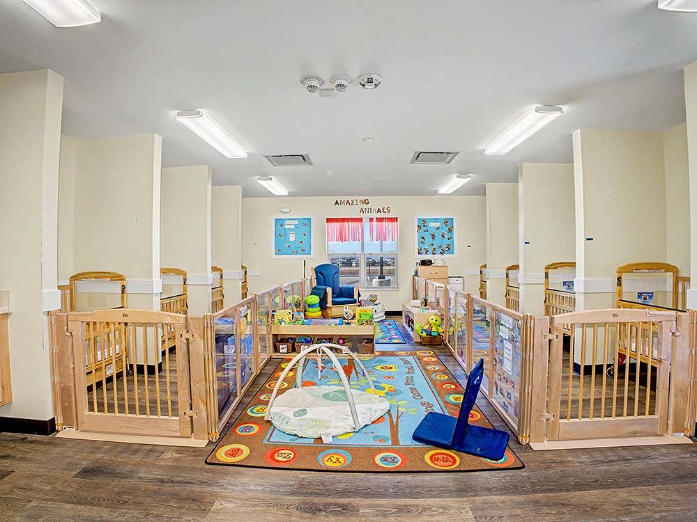 Baby room with multiple cribs, a play area, and windows with 