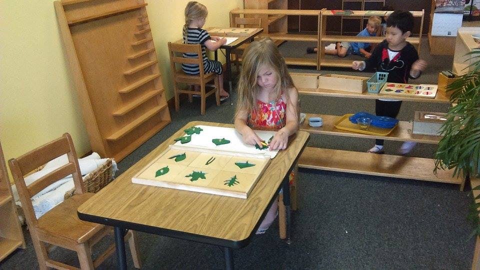 Child working with puzzle pieces at a table in a classroom