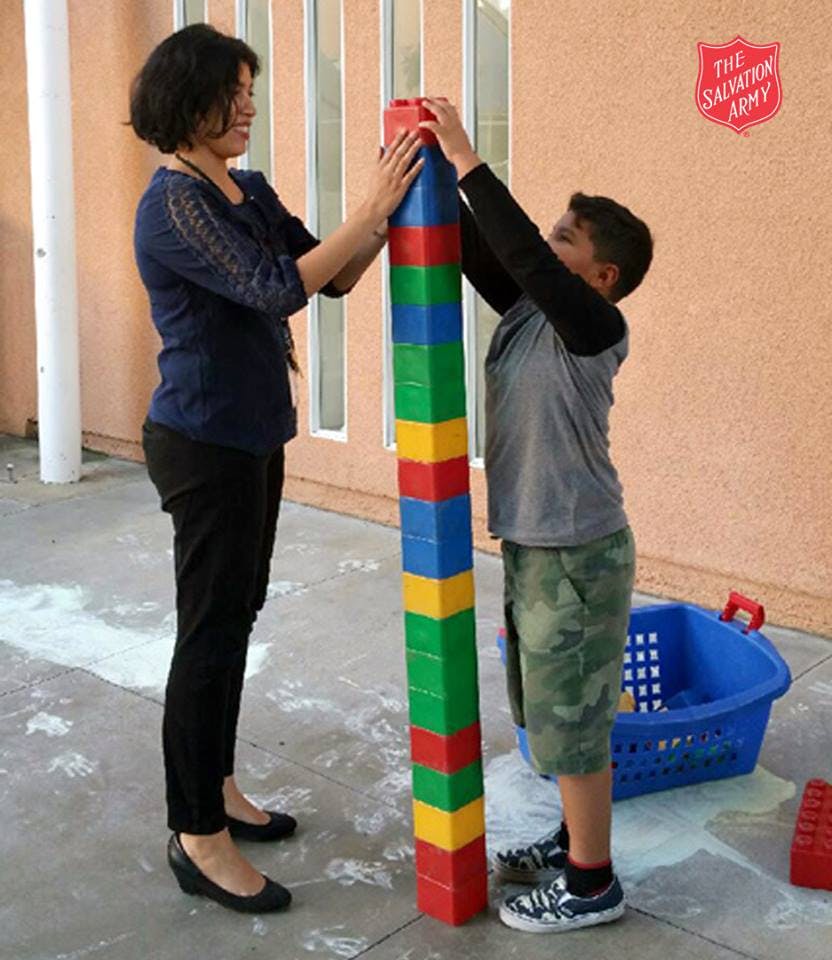 Person and child building a tall tower with large colorful blocks