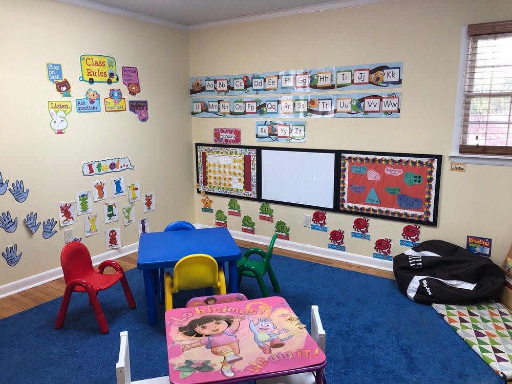 Classroom with small tables and chairs, decorated walls, and a whiteboard