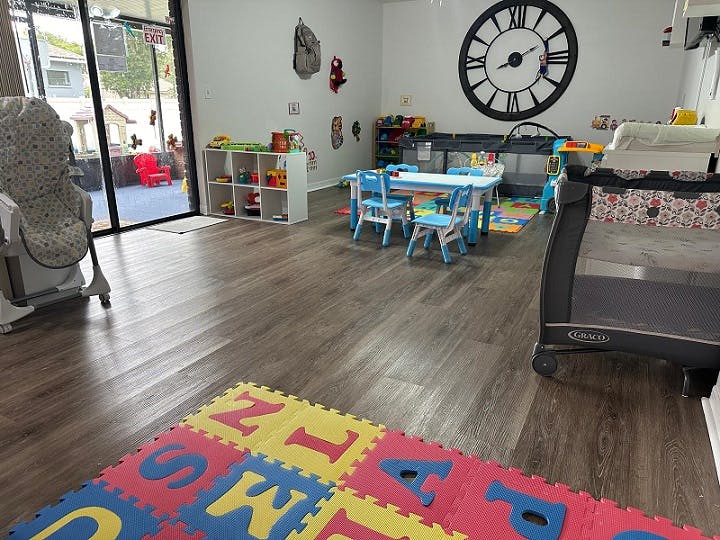 Playroom with small tables and chairs, crib, and alphabet mat
