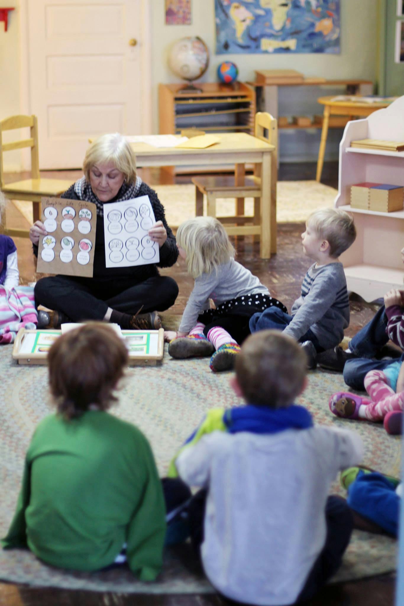 Person showing children papers with drawings in a classroom