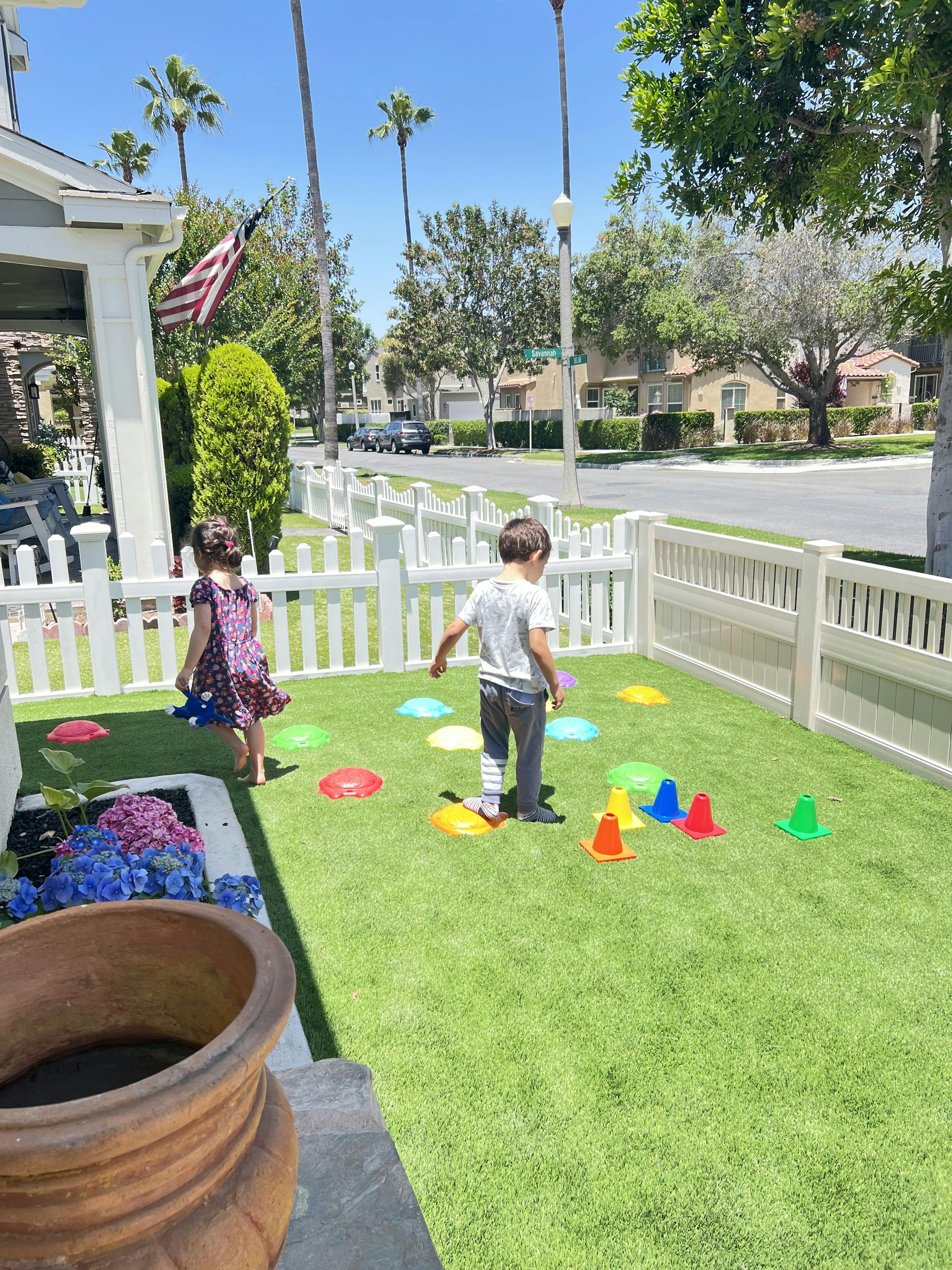 Two children playing on a lawn with colorful markers
