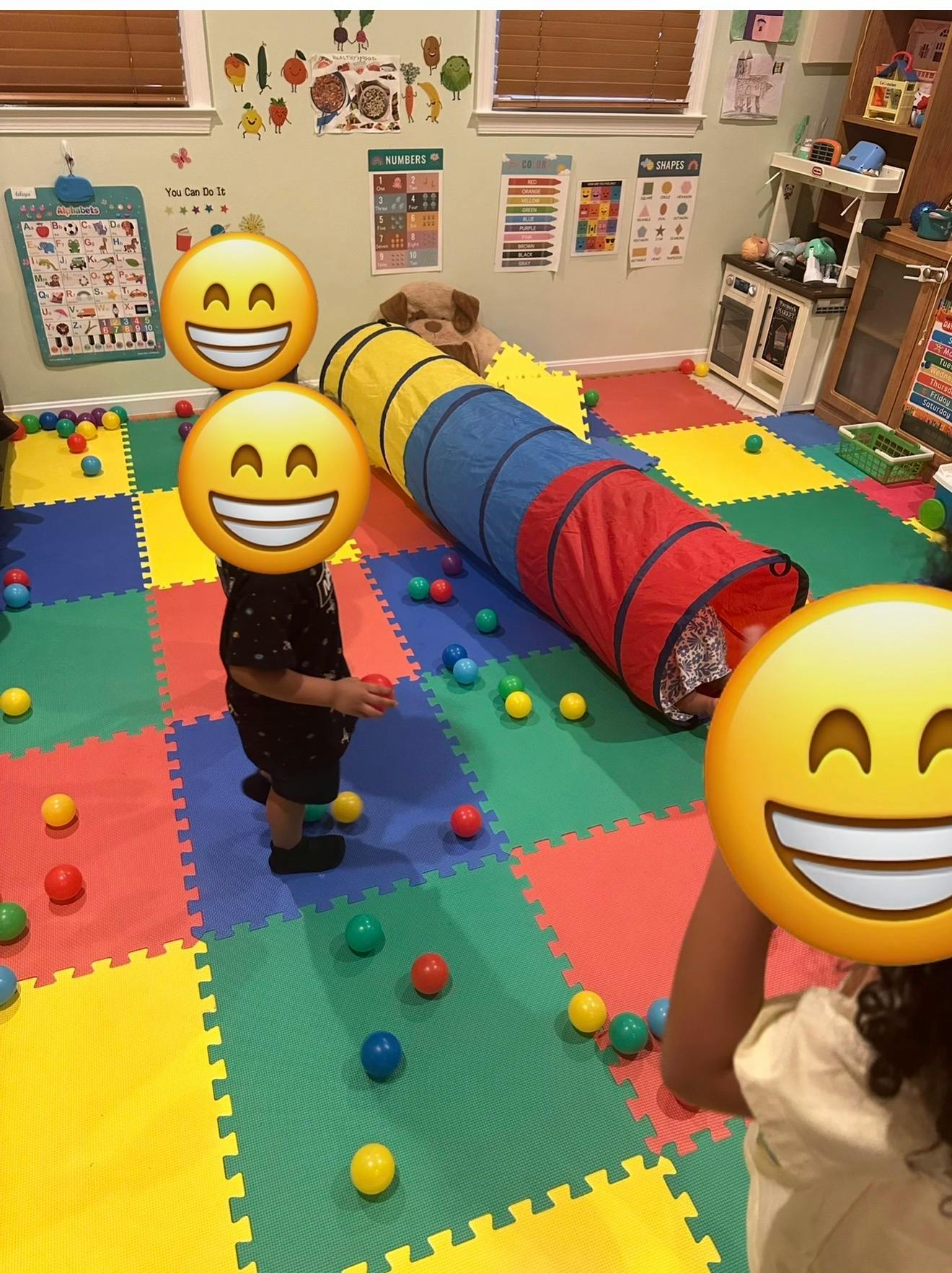 Children playing with a ball pit and tunnel in a colorful room