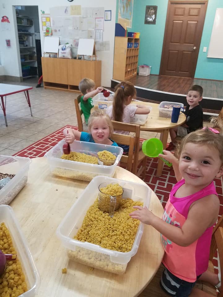 Children playing with dried pasta in a classroom