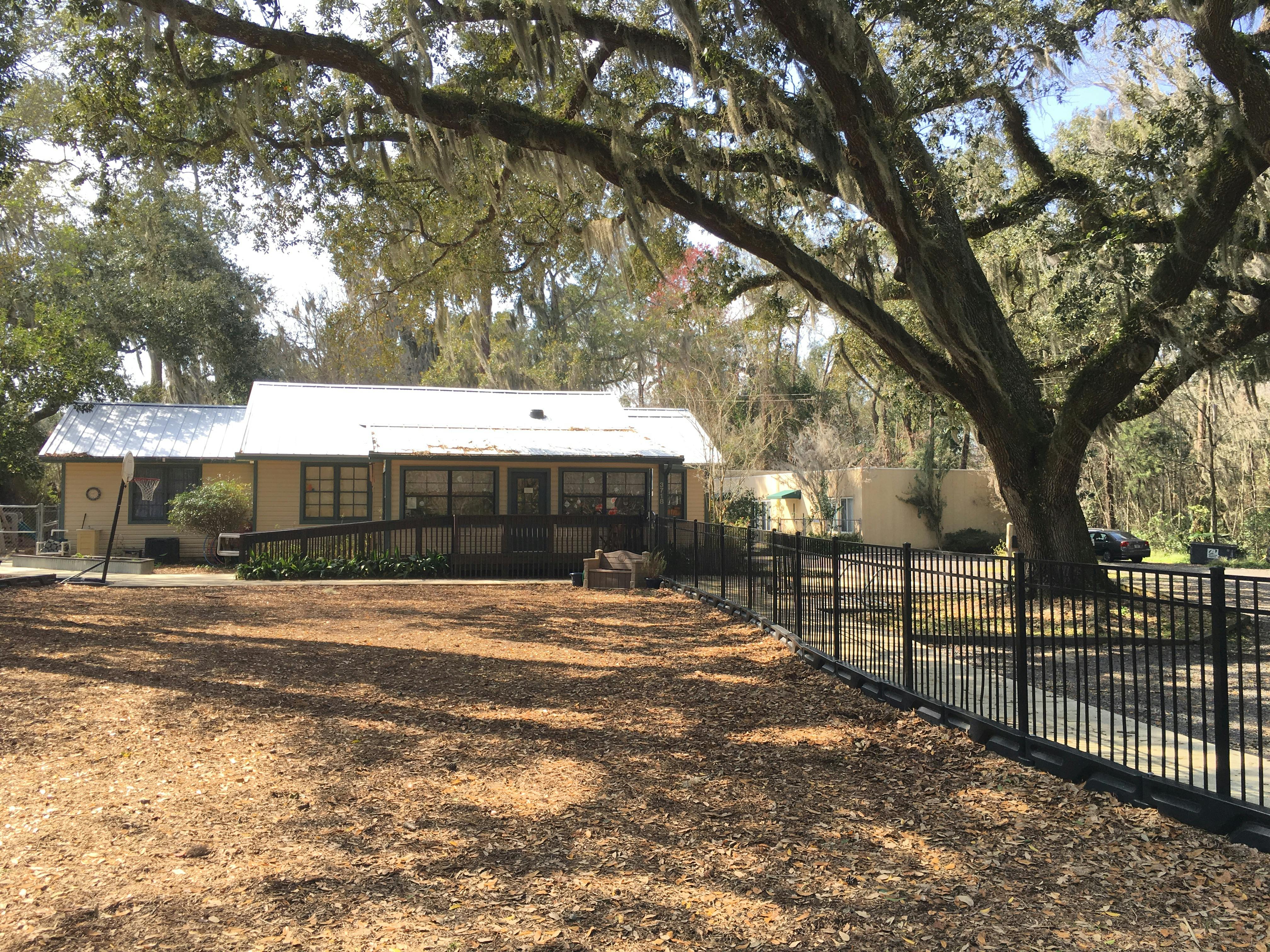 Building with a ramp and a large tree in front of a fence