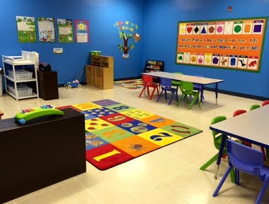 Classroom with colorful rug, small tables, and educational posters on walls