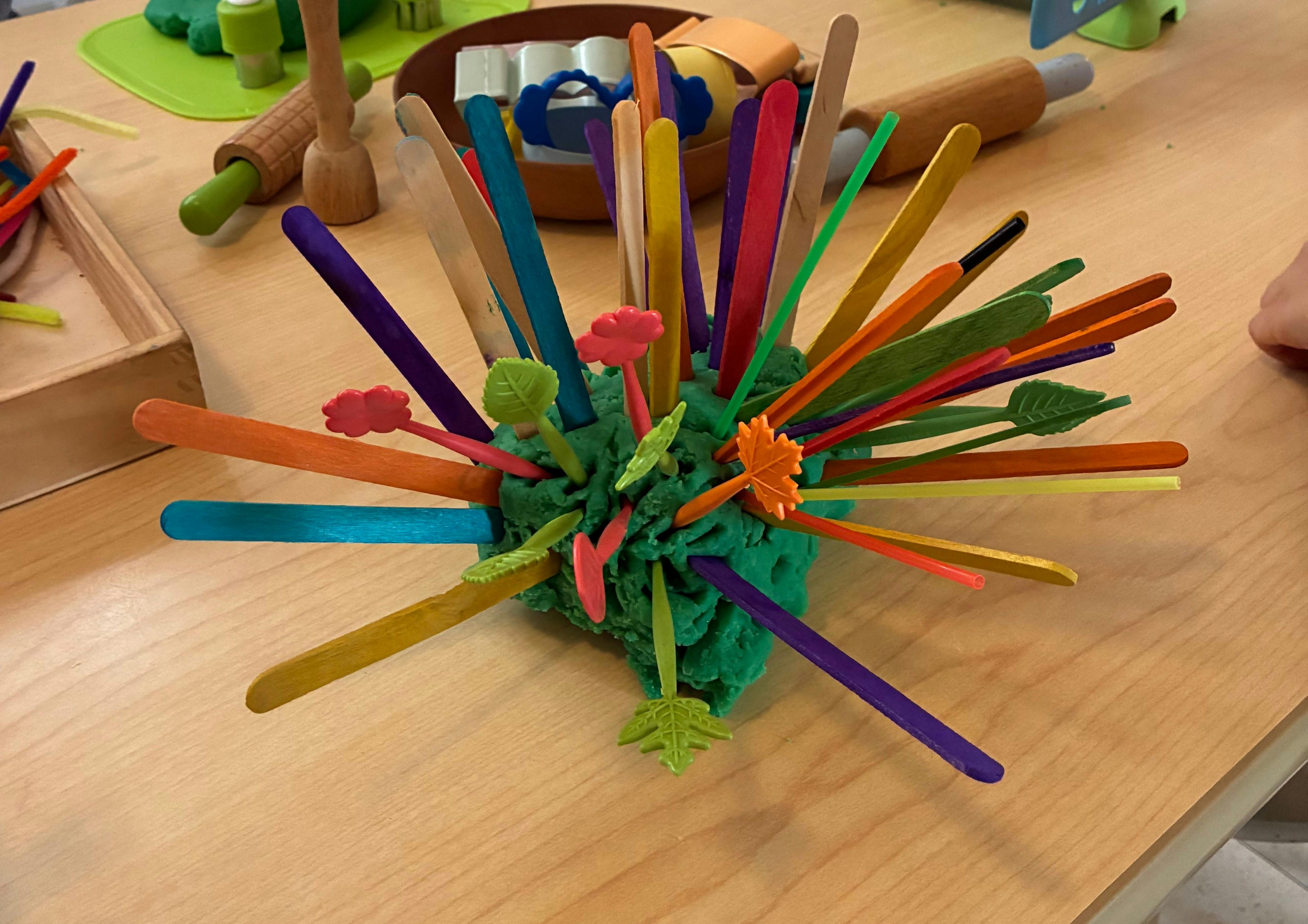 Colorful craft sticks inserted into a ball of green playdough