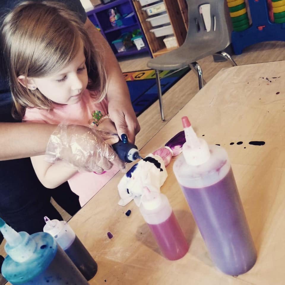 Child and person tie-dyeing fabric with squeeze bottles