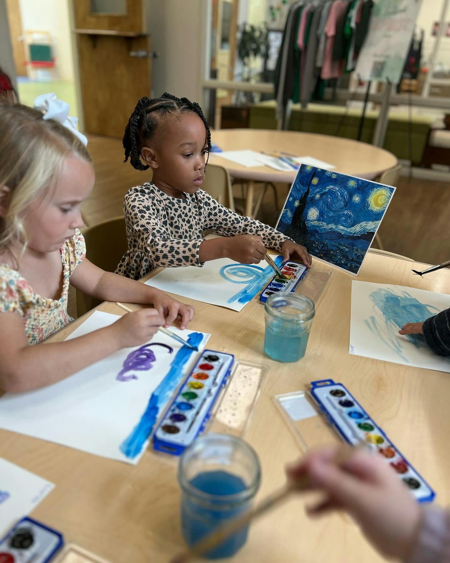 Two children painting with watercolors at a table