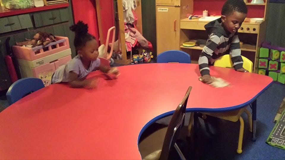 Two children playing on a red table