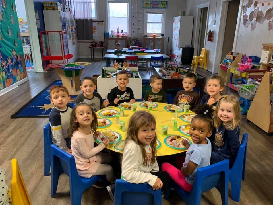 Group of children sitting around a yellow table in a classroom