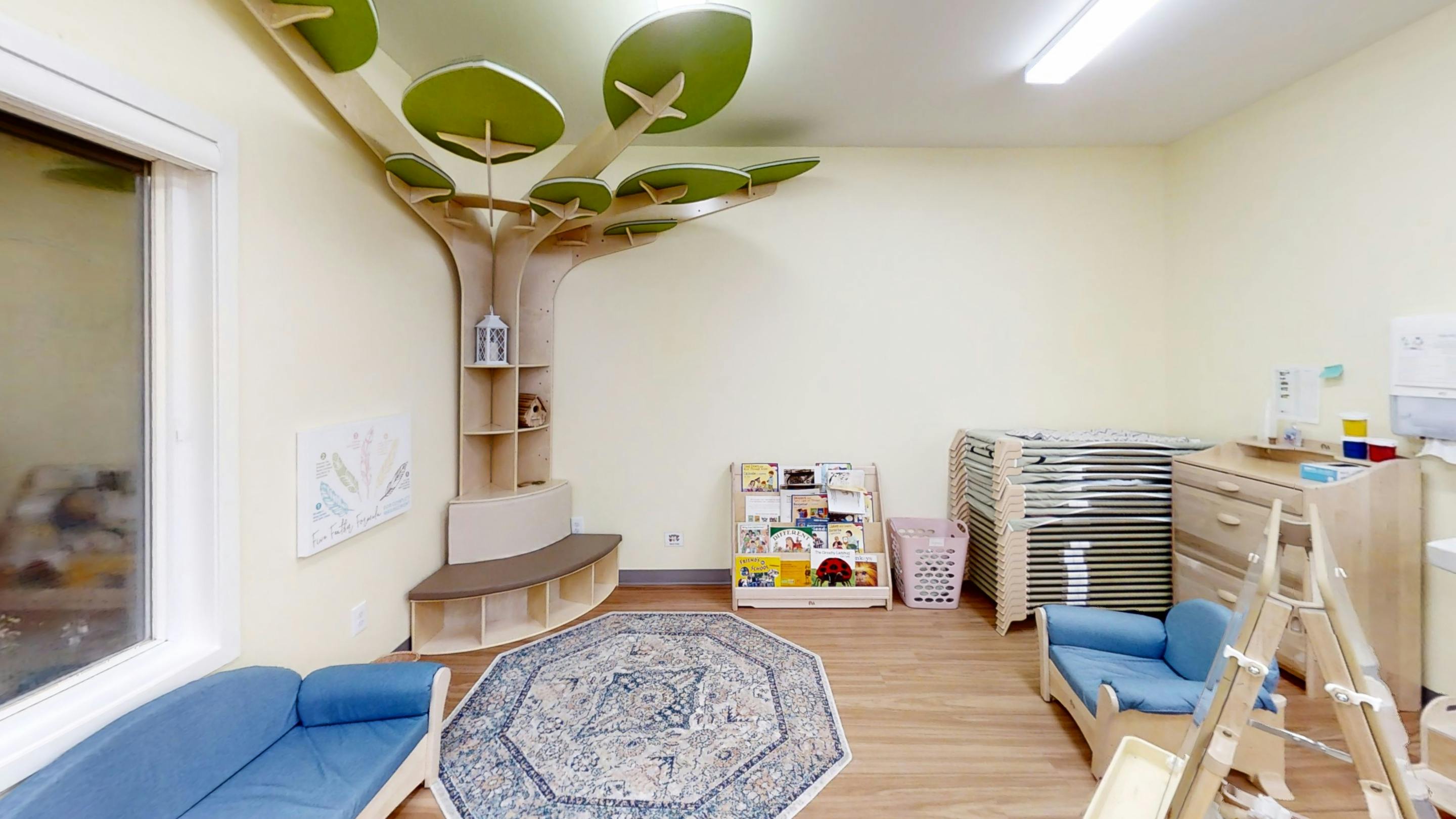 Children's room with tree-shaped shelving, blue sofa, and rug