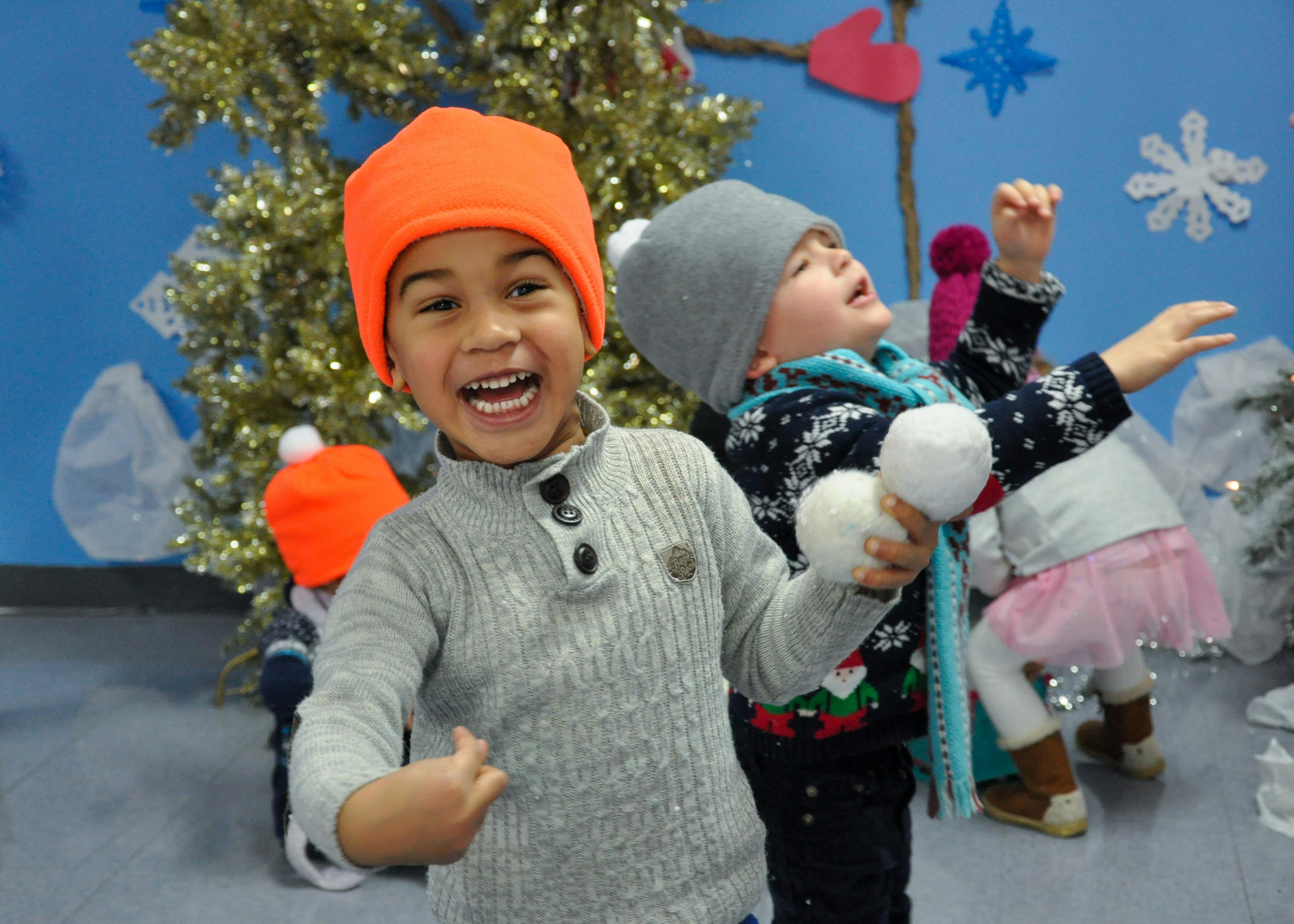 Two children in winter hats playing with white pom-poms