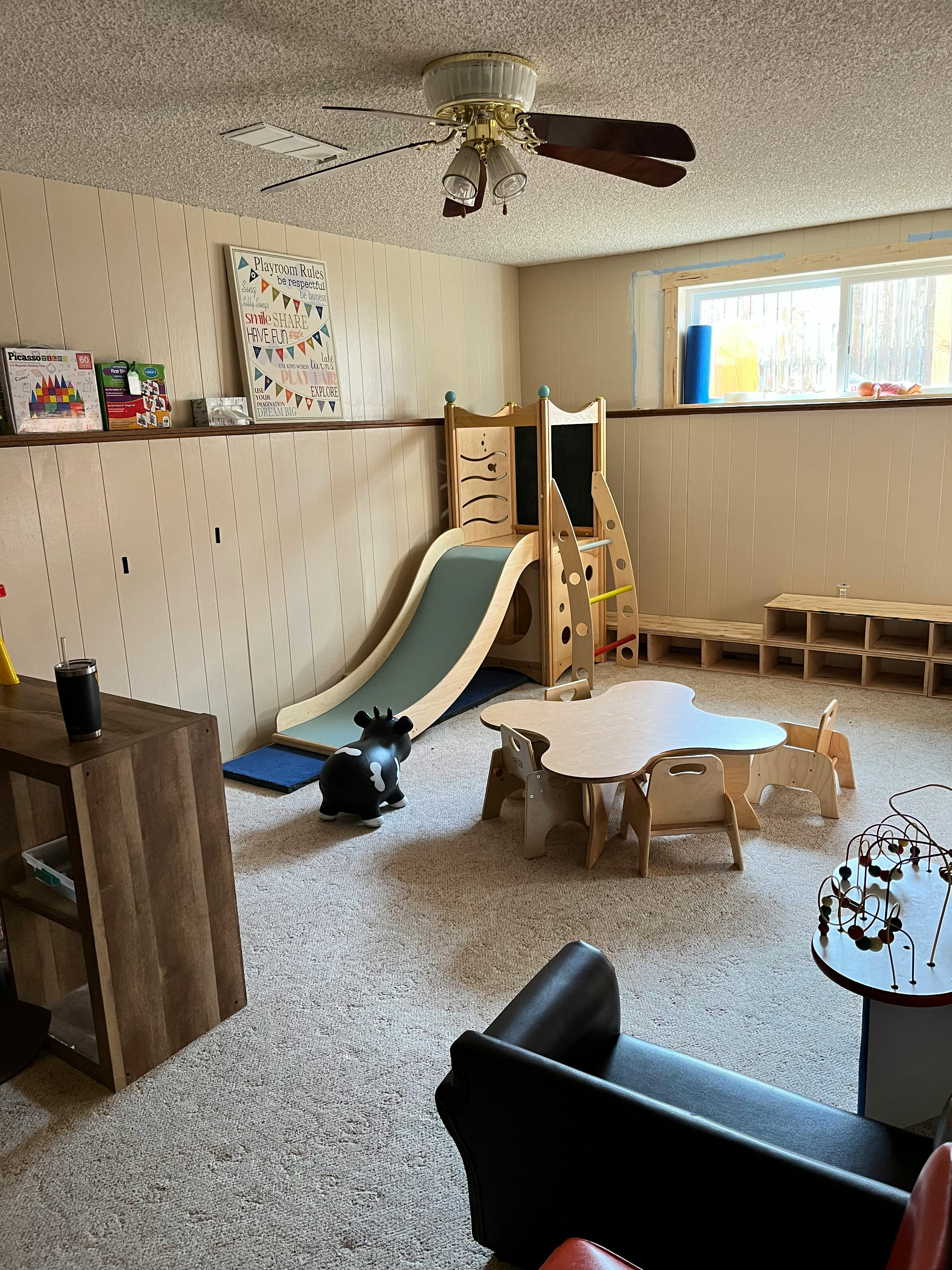 Indoor play area with a slide, small table and chairs, and a rocking toy