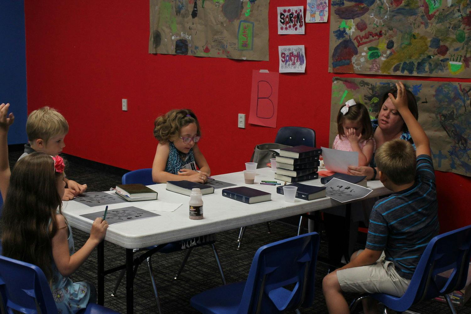 Adult and children sitting at a table with books and papers