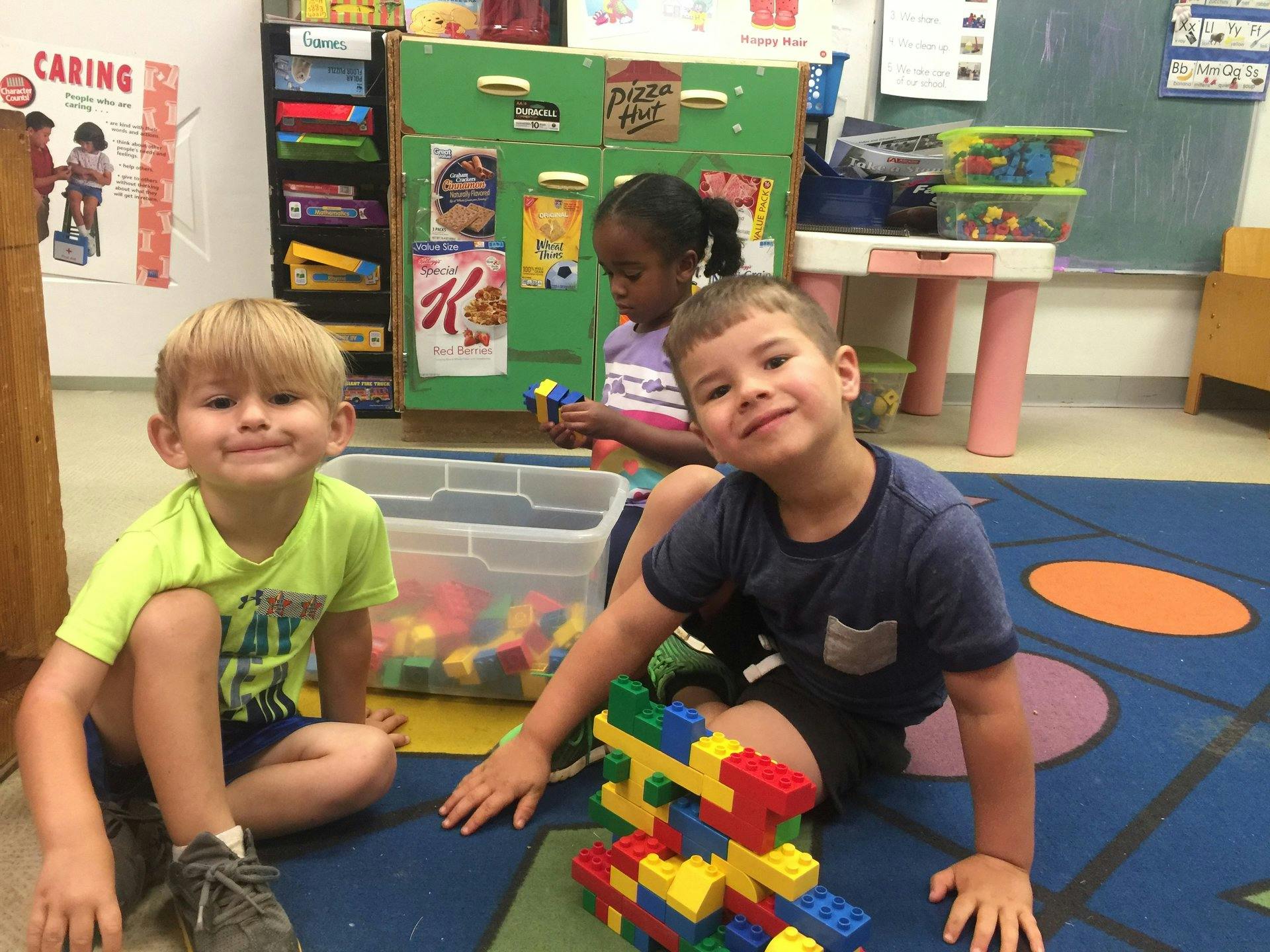 Three children playing with building blocks in a classroom