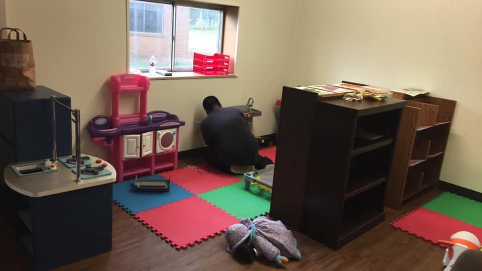 Person kneeling on floor in a room with colorful mats and toys
