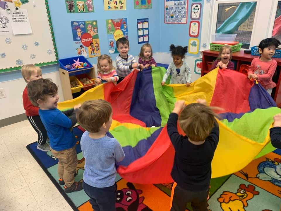 Children playing with a colorful parachute in a classroom