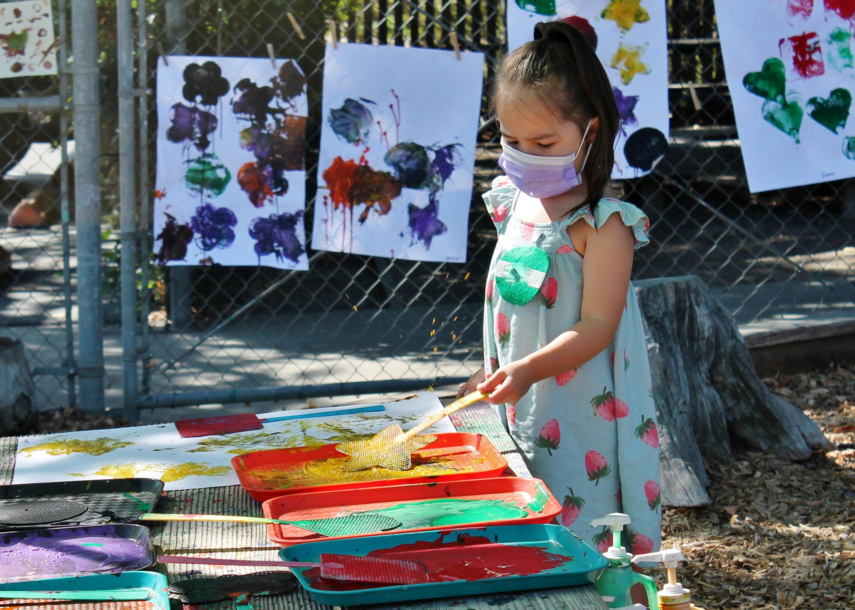 Child in a mask painting outdoors