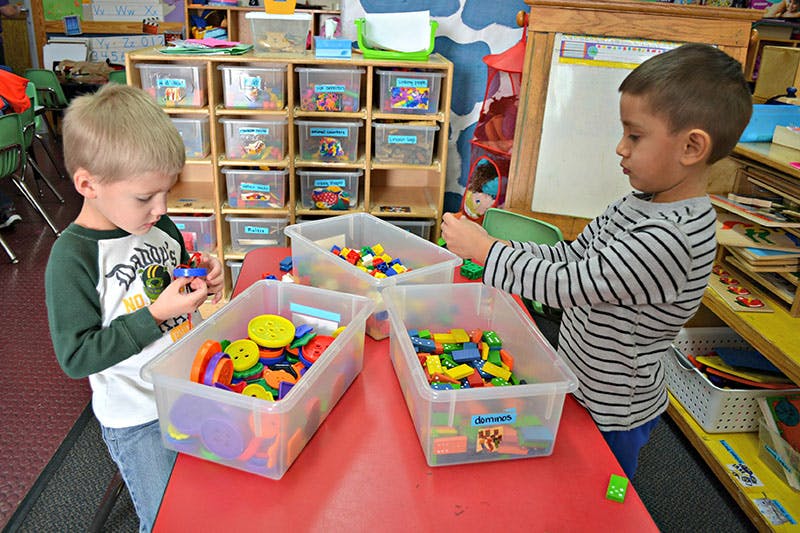 Two children playing with colorful blocks and toys at a table