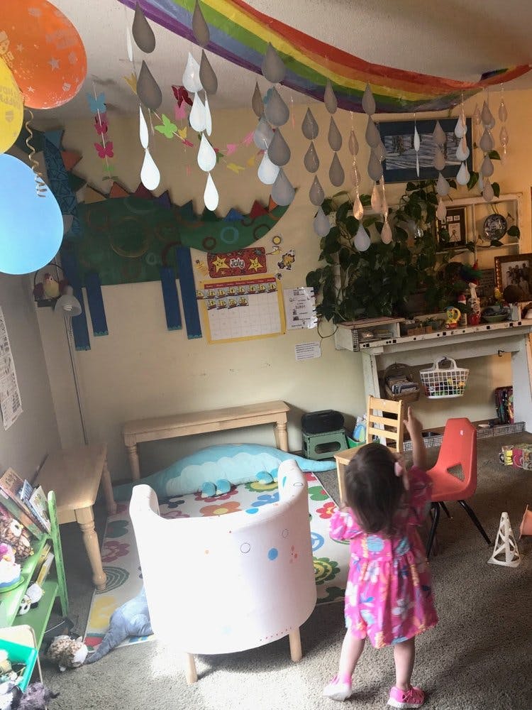 Child in a pink dress reaching up in a decorated room