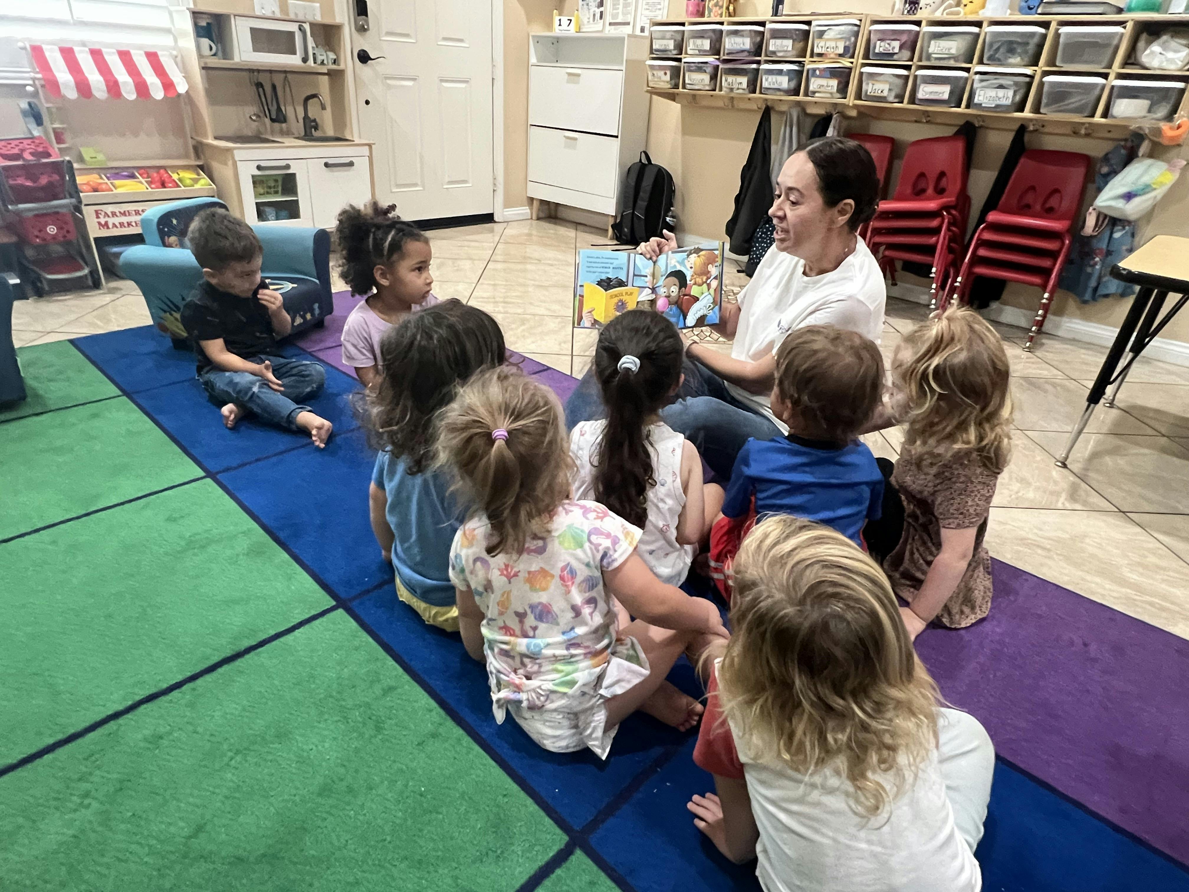 Person reading a book to a group of children in a classroom