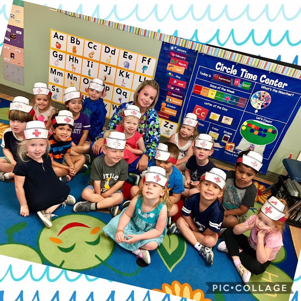 Adult and children wearing nurse hats in a classroom