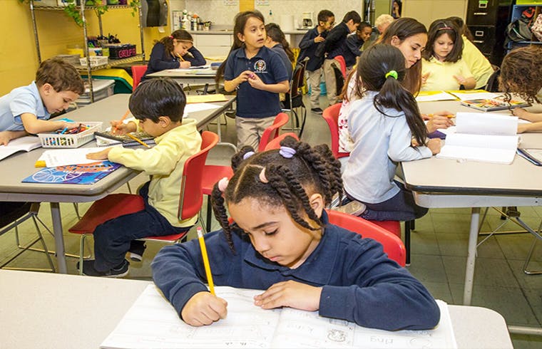 Children writing and working at desks in a classroom