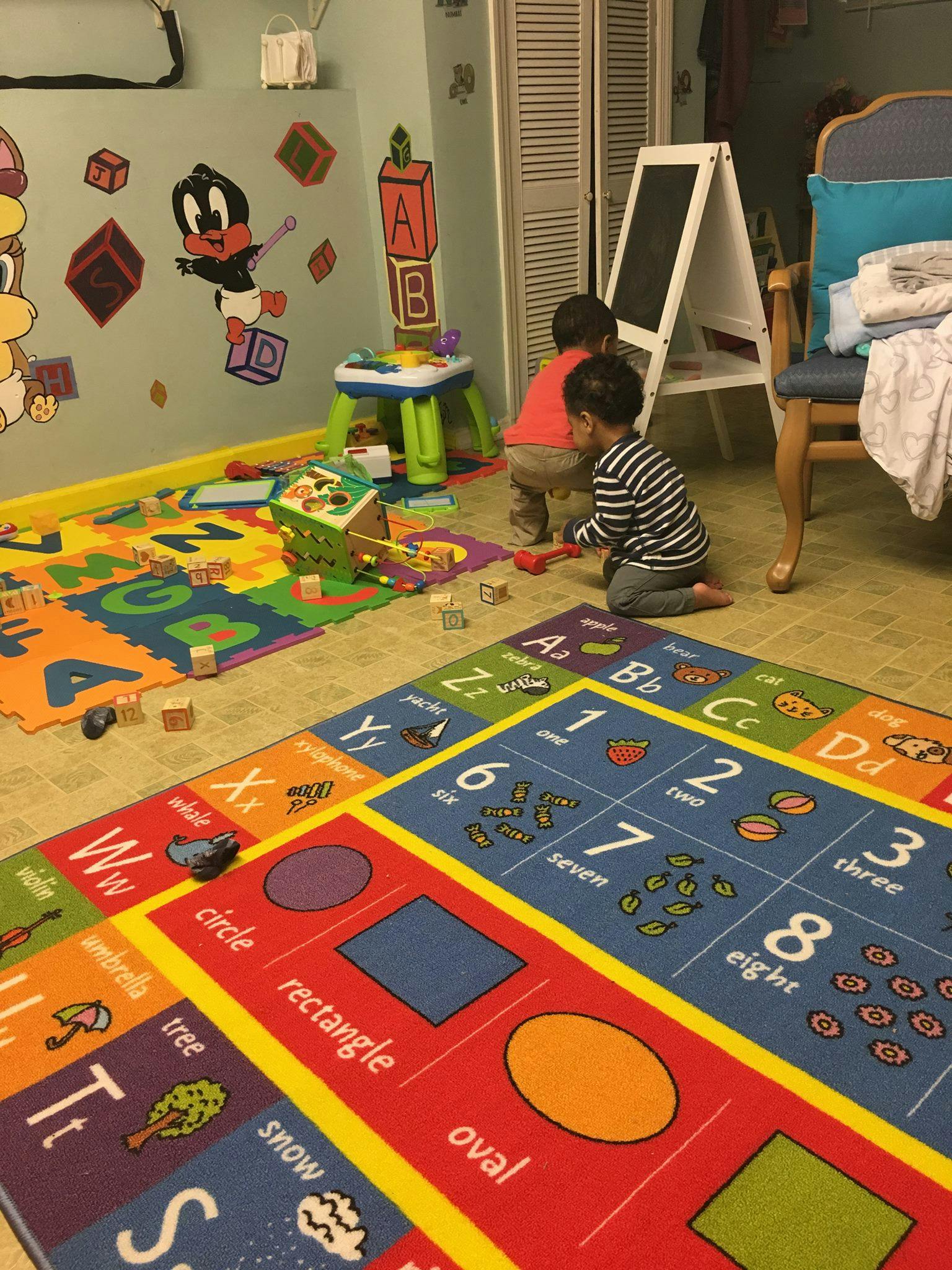 Two children playing on a colorful alphabet and numbers rug