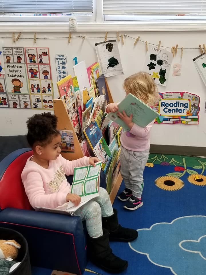Two children reading books in a classroom