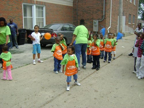 Adults and children in matching shirts and aprons standing outdoors