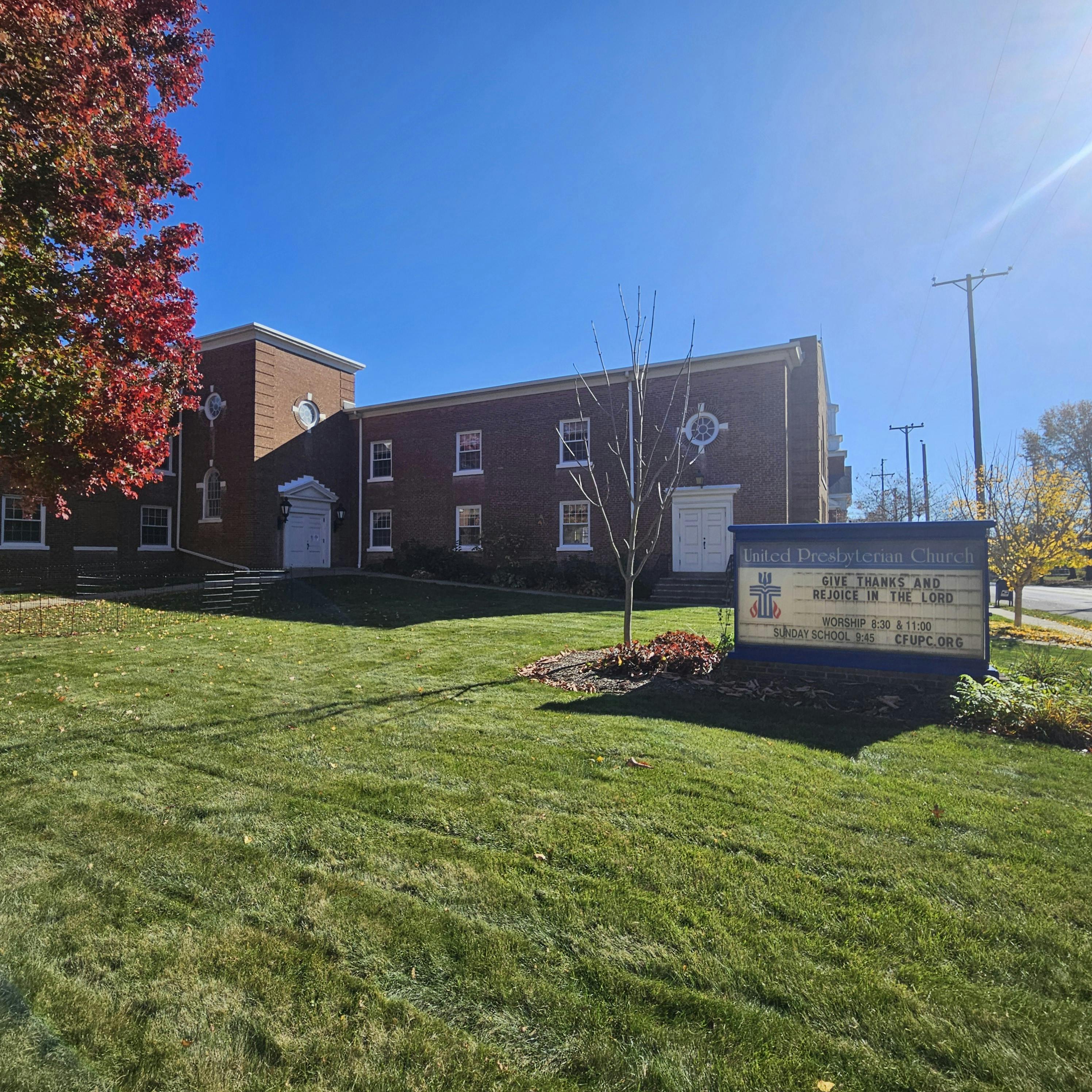 Brick building with a sign in front on a grassy lawn