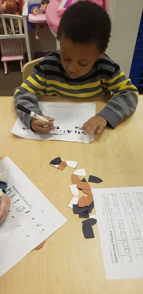 Child writing on a worksheet at a table