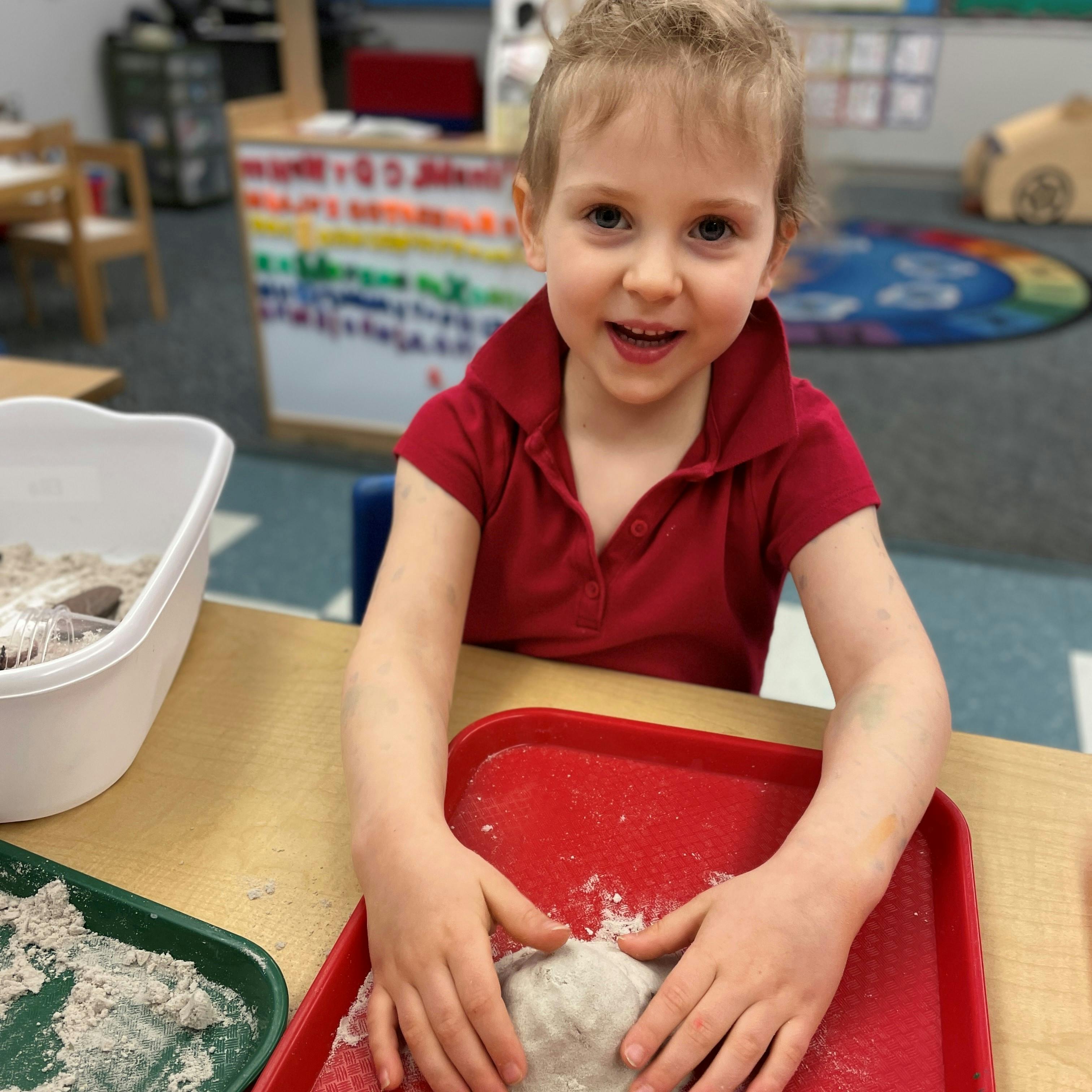 Child playing with dough in a classroom