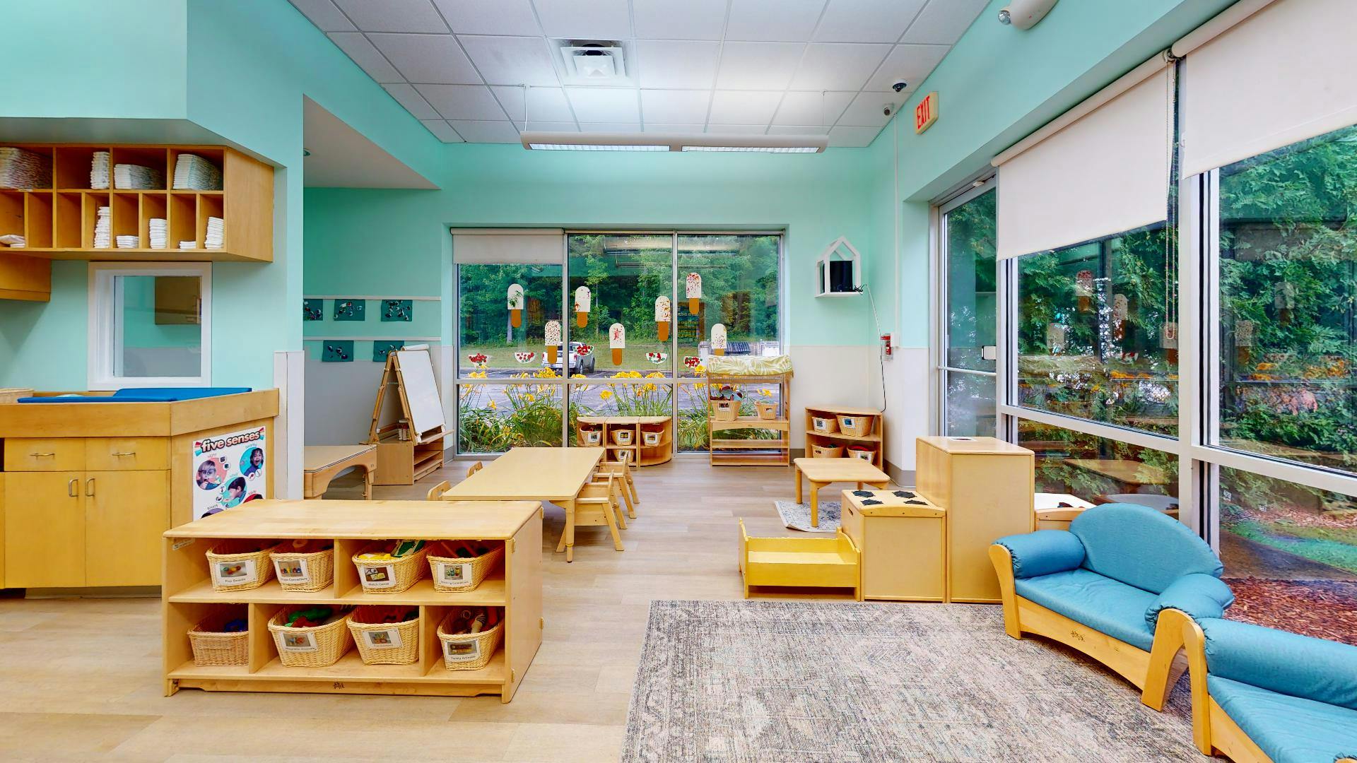 Classroom with wooden furniture, small tables, and blue couches