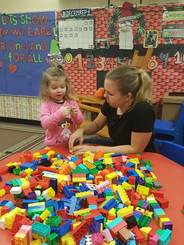 Adult and child playing with colorful building blocks at a table