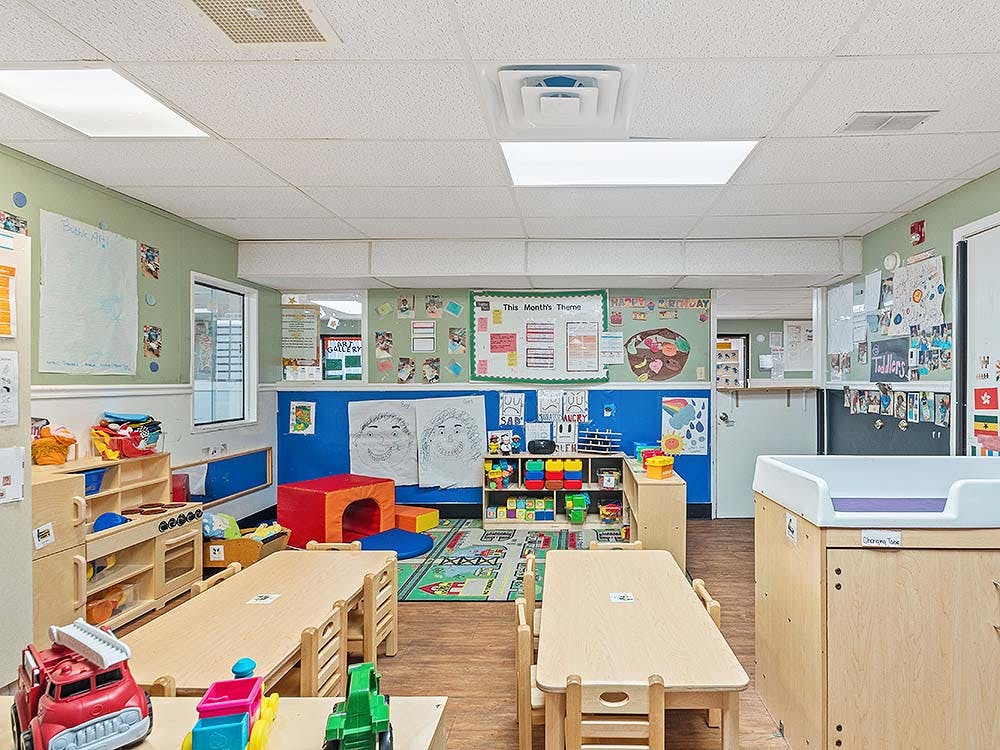 Colorful classroom with small tables, chairs, and play areas
