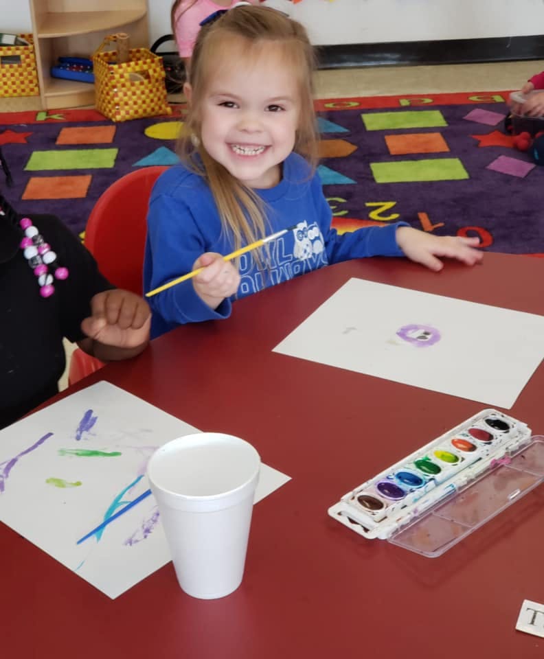 Child painting with watercolors at a table