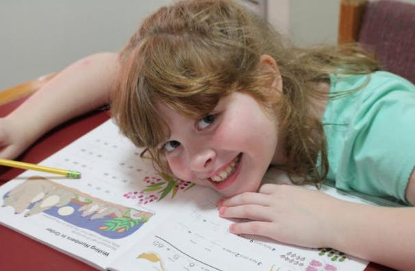 Child lying on a book with a pencil nearby